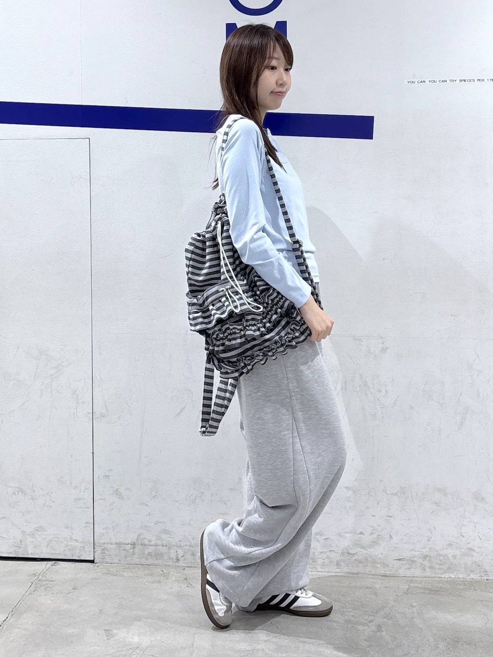 グレー系のスウェットパンツ、ブルー系のTシャツ/カットソー、グレー系のバックパック/リュックを着用したレディースの秋コーディネートの3枚目の写真
