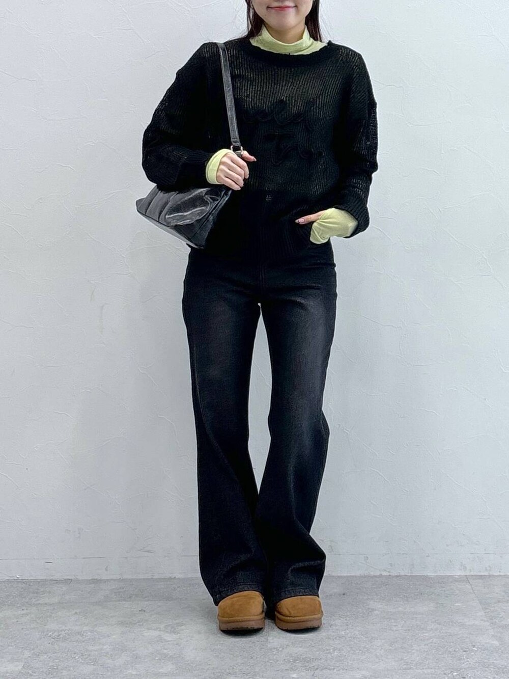ブラック系のデニムパンツ、ブラック系のハンドバッグ、グリーン系のTシャツ/カットソーを着用したレディースの冬コーディネートの2枚目の写真