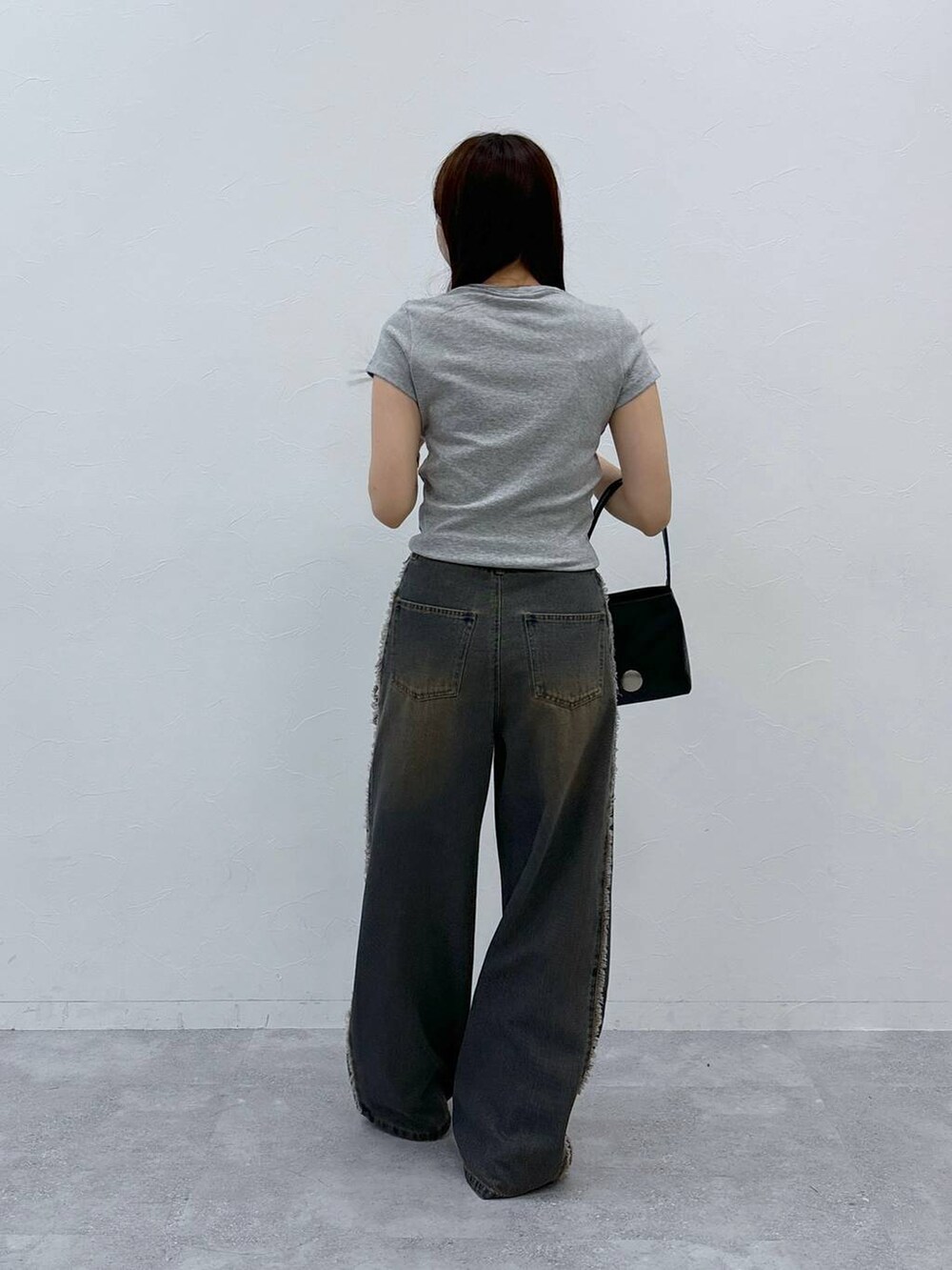 ブルー系のデニムパンツ、グレー系のTシャツ/カットソー、ブラック系のハンドバッグを着用したレディースの夏コーディネートの4枚目の写真