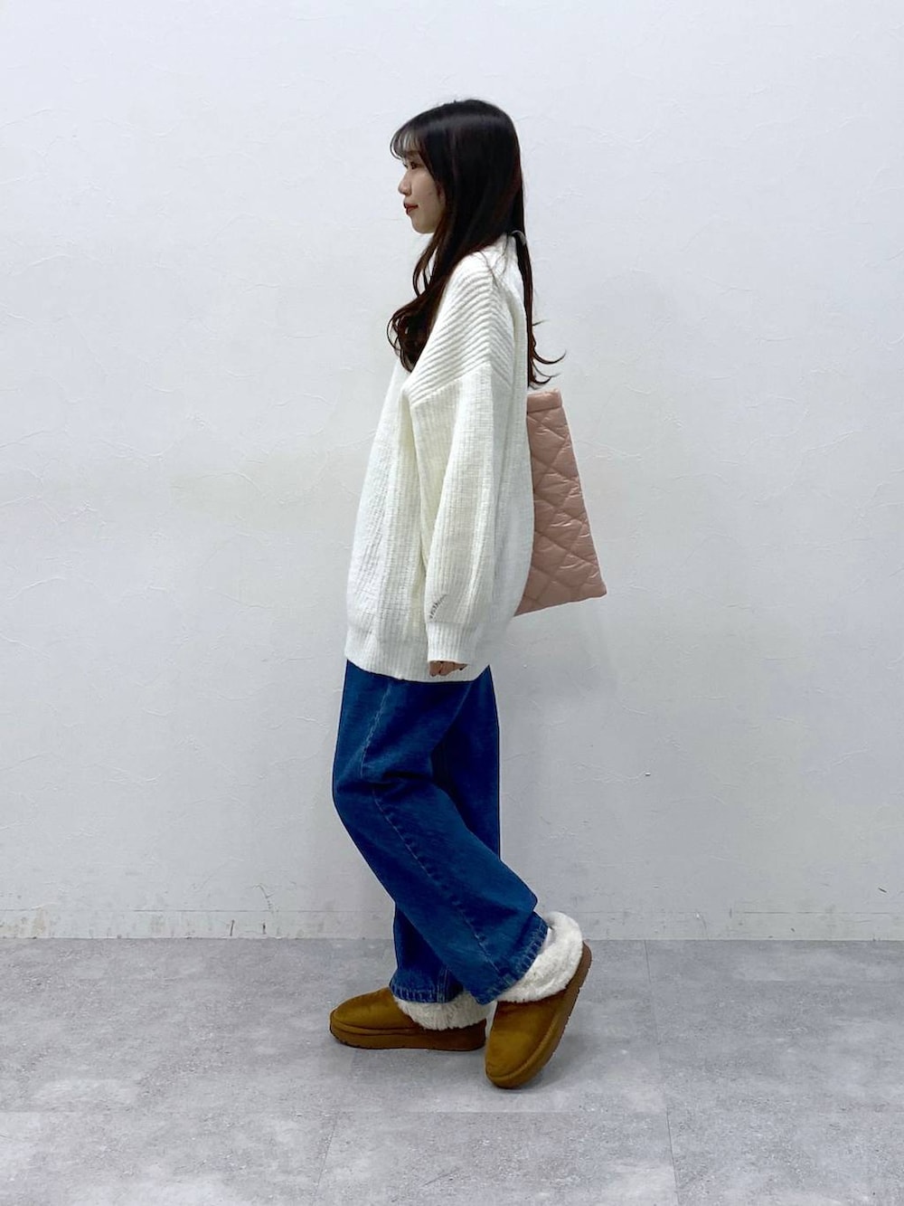 ピンク系のトートバッグ、ブルー系のデニムパンツ、ホワイト系のニット/セーターを着用したレディースの冬コーディネートの4枚目の写真
