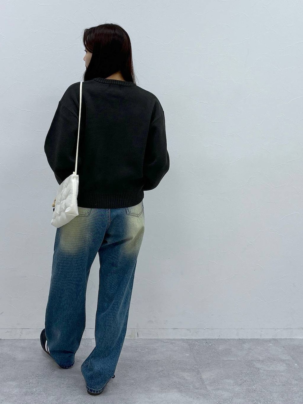 ブルー系のデニムパンツ、ホワイト系のショルダーバッグ、グレー系のニット/セーターを着用したレディースの秋コーディネートの4枚目の写真