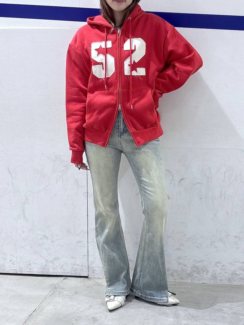 ブルー系のデニムパンツ、ホワイト系のパンプス、レッド系のパーカーを着用したレディースの春コーディネートの2枚目の写真