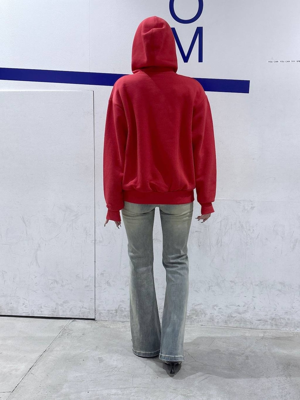 ブルー系のデニムパンツ、ホワイト系のパンプス、レッド系のパーカーを着用したレディースの春コーディネートの4枚目の写真