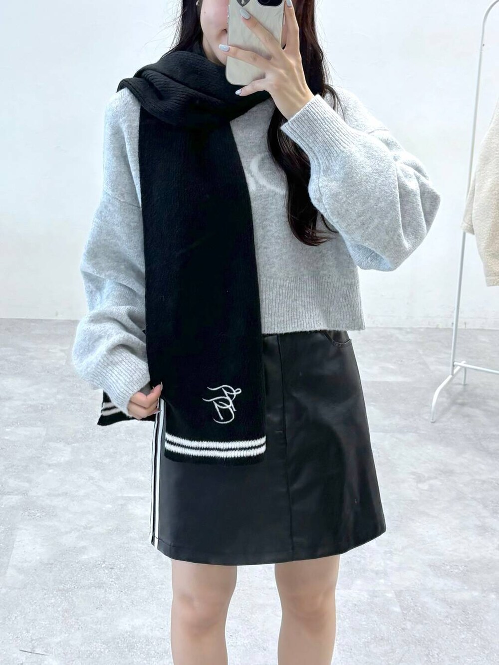 ブラック系のショルダーバッグ、グレー系のニット/セーター、ブラック系のスカートを着用したレディースの秋コーディネートの6枚目の写真