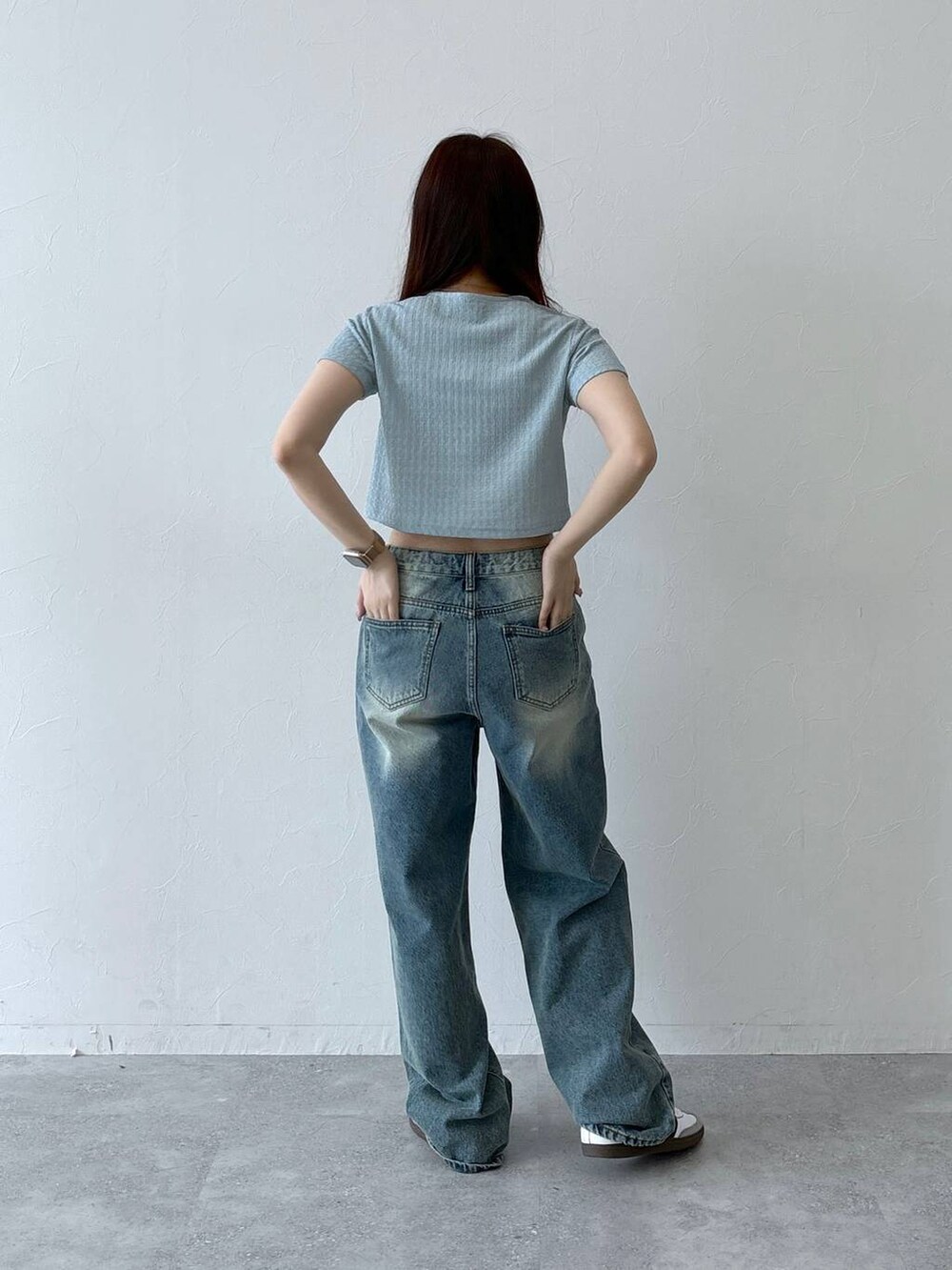 ブルー系のデニムパンツ、ベージュ系のチューブトップ、ブルー系のTシャツ/カットソーを着用したレディースの春コーディネートの4枚目の写真