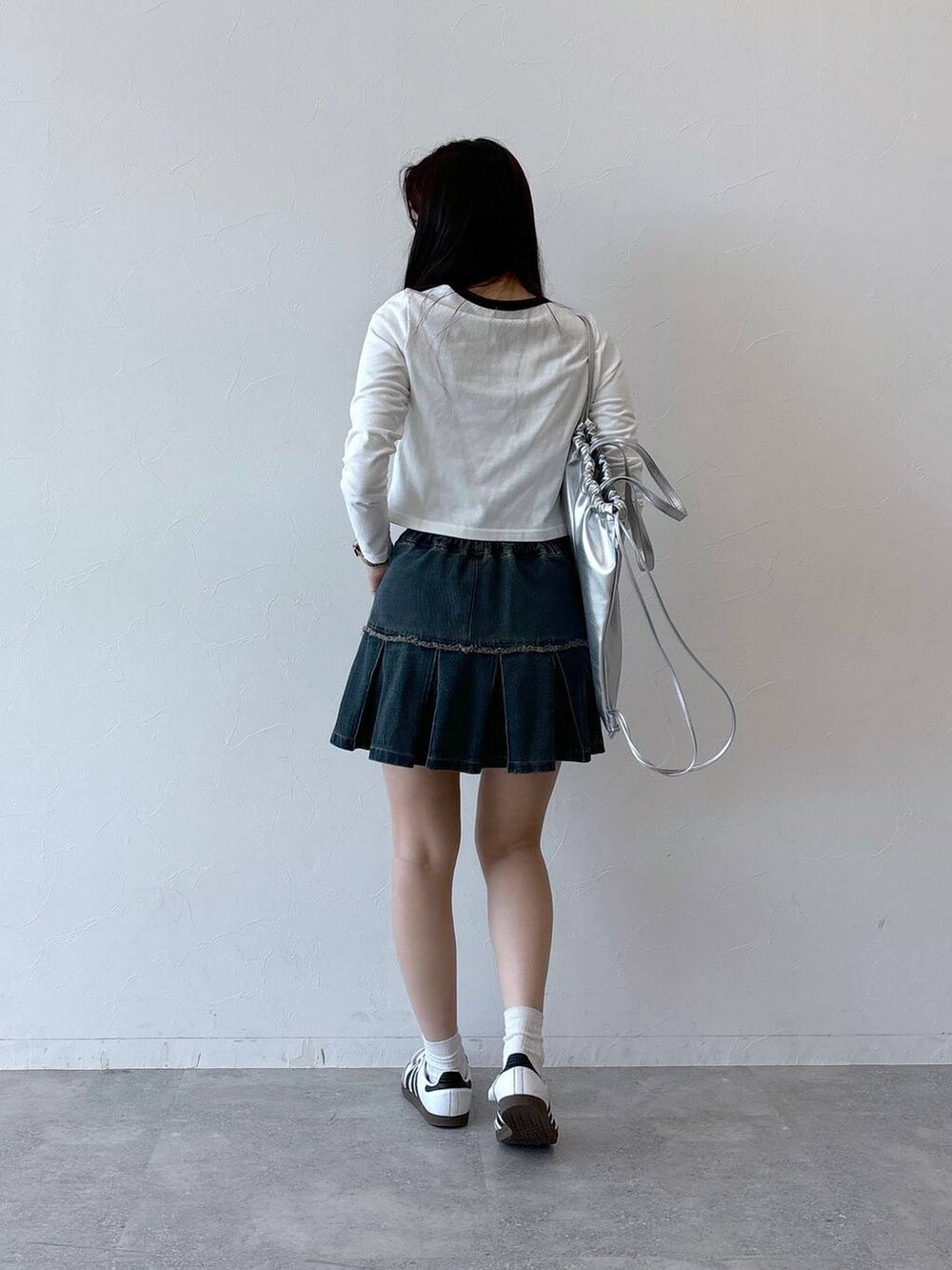 ブルー系のデニムスカート、ホワイト系のTシャツ/カットソー、グレー系のバックパック/リュックを着用したレディースの秋コーディネートの4枚目の写真