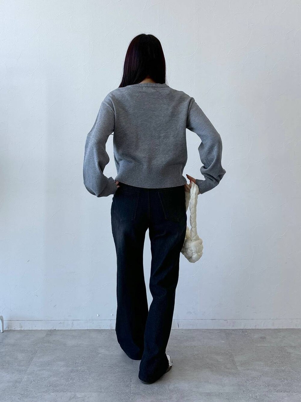 ホワイト系のショルダーバッグ、ブラック系のデニムパンツ、グレー系のニット/セーターを着用したレディースの冬コーディネートの4枚目の写真