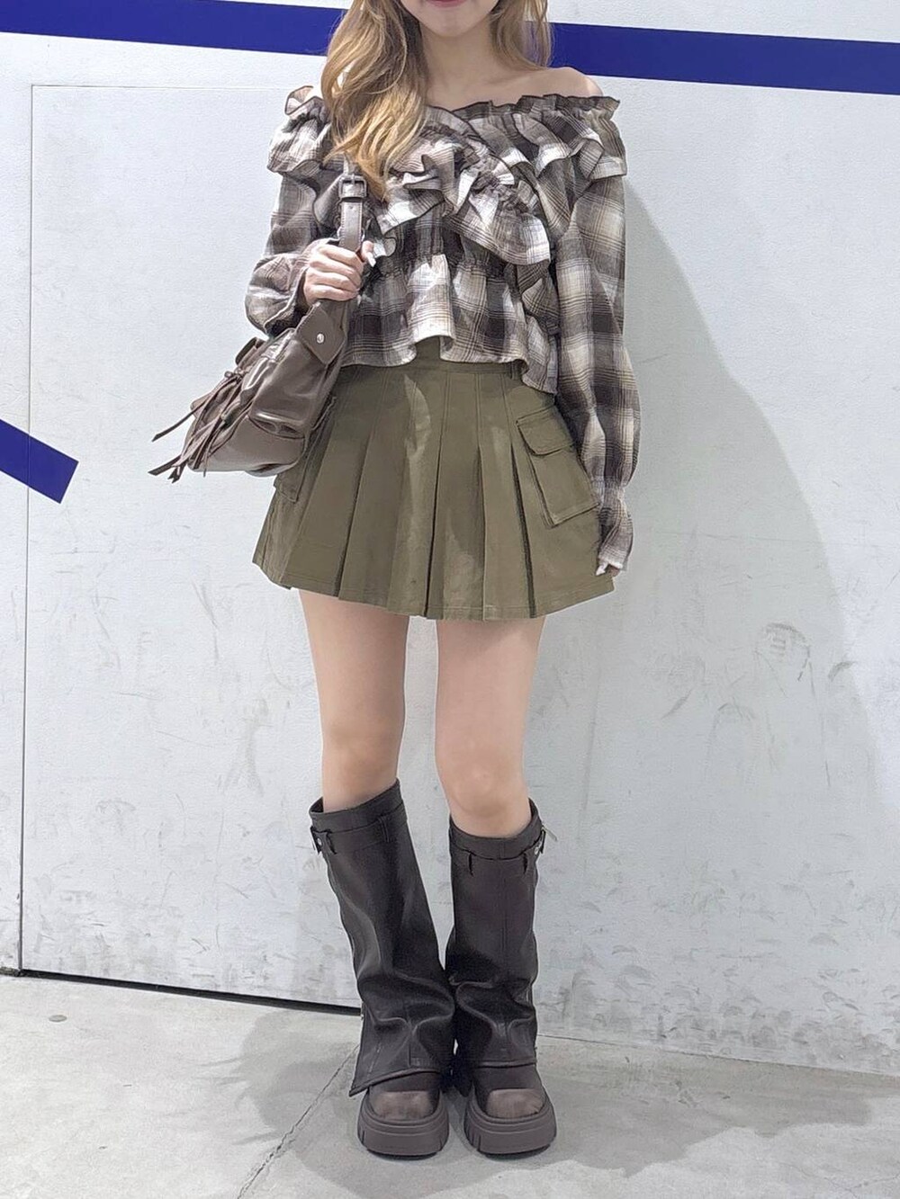 ブラウン系のショルダーバッグ、ベージュ系のスカート、ブラウン系のブーツを着用したレディースの秋コーディネートの2枚目の写真