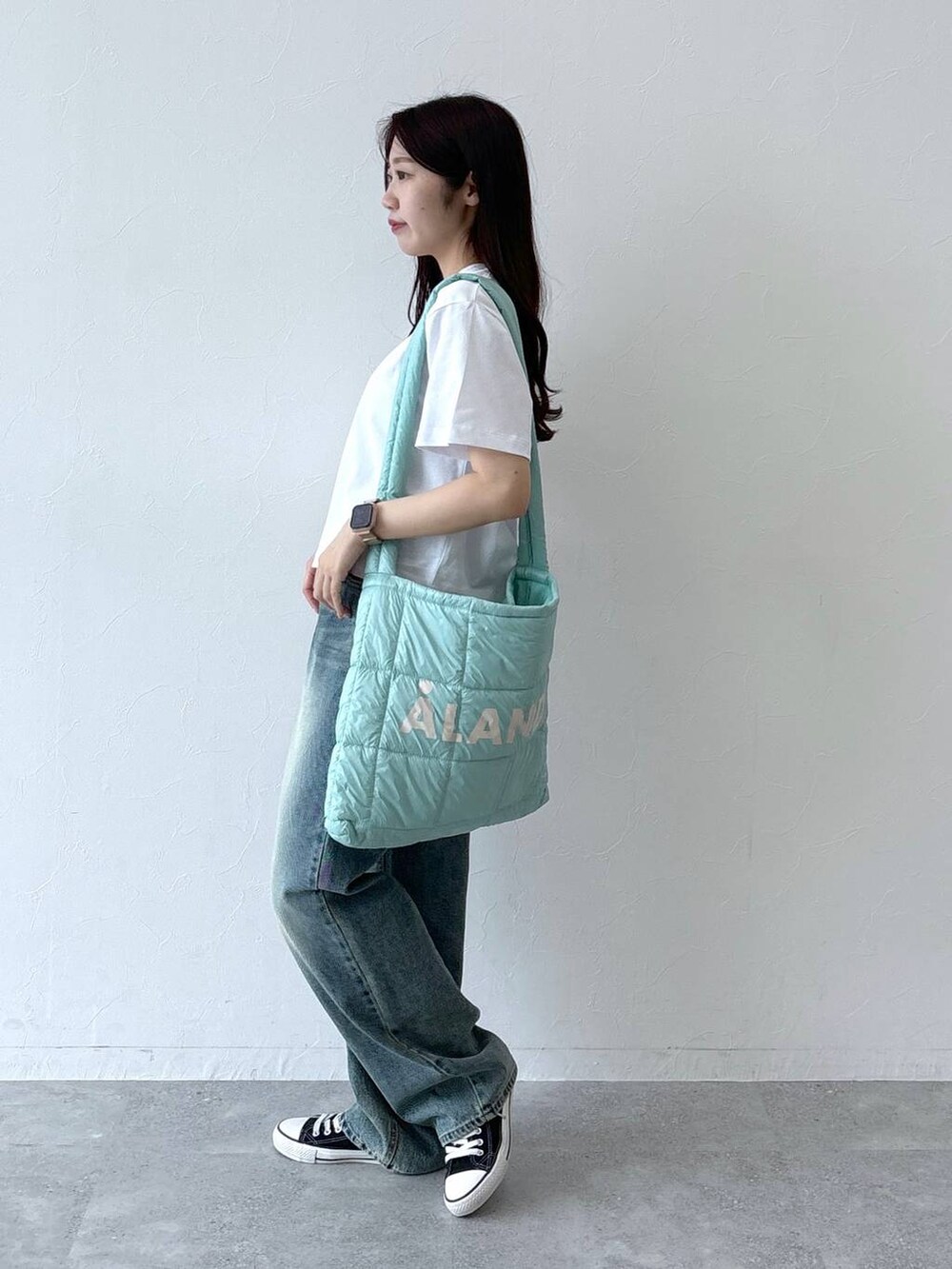 ブルー系のデニムパンツ、グリーン系のショルダーバッグ、ホワイト系のTシャツ/カットソーを着用したレディースの夏コーディネートの4枚目の写真