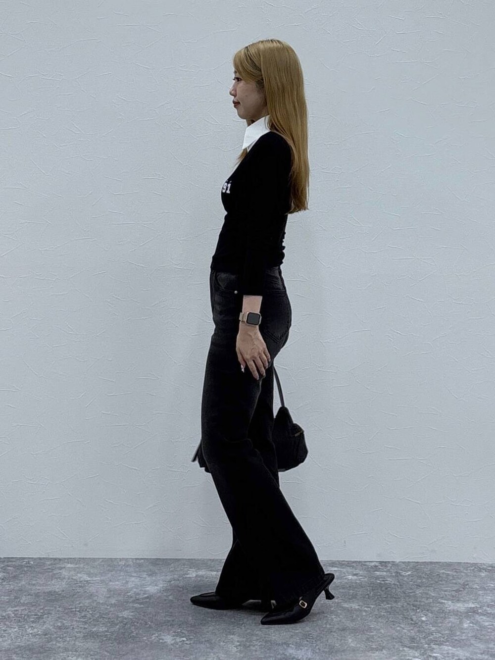 ブラック系のローファー、グレー系のハンドバッグ、ブラック系のデニムパンツを着用したレディースの秋コーディネートの4枚目の写真