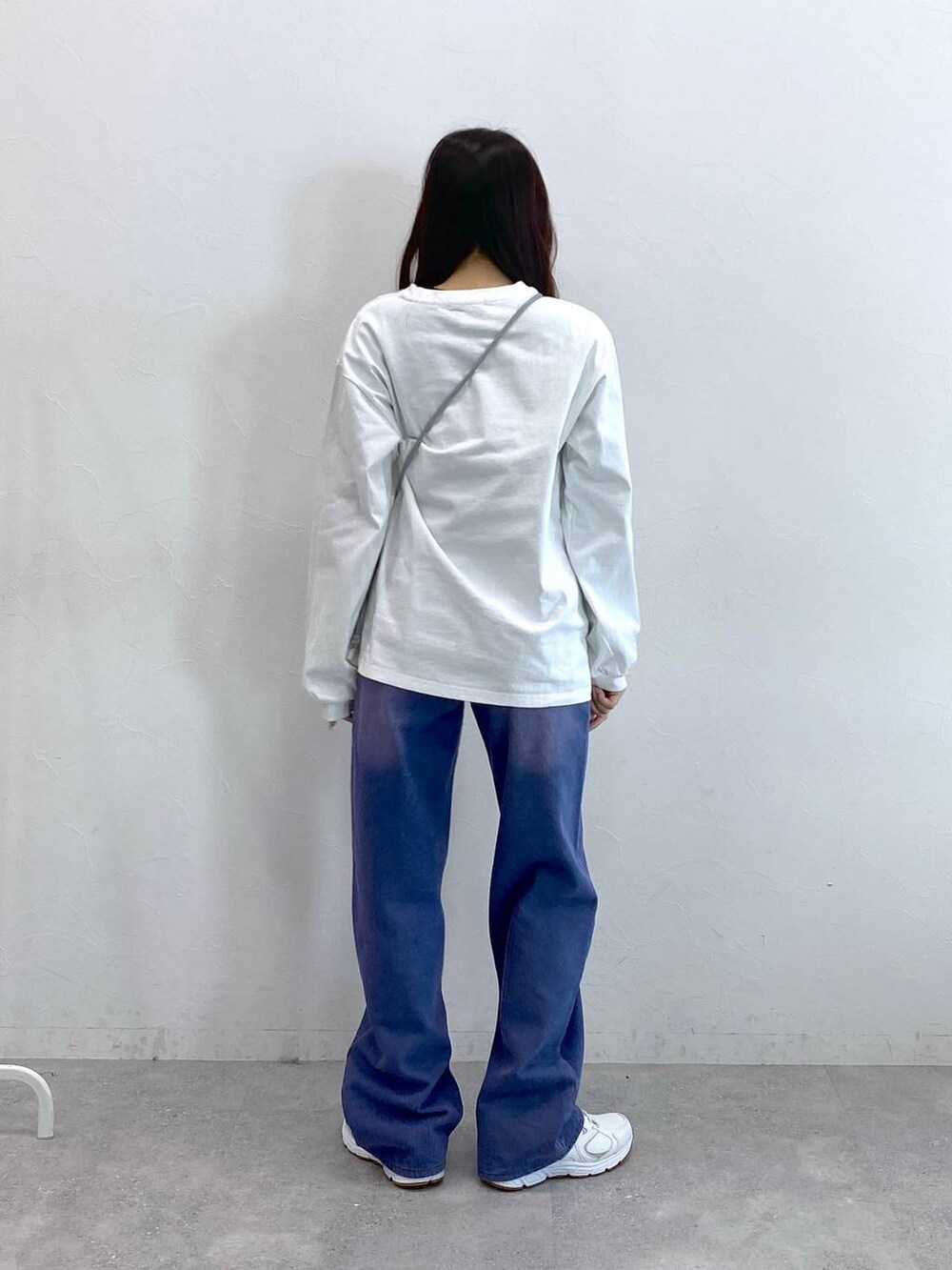 パープル系のデニムパンツ、グレー系のショルダーバッグ、ホワイト系のTシャツ/カットソーを着用したレディースの冬コーディネートの4枚目の写真