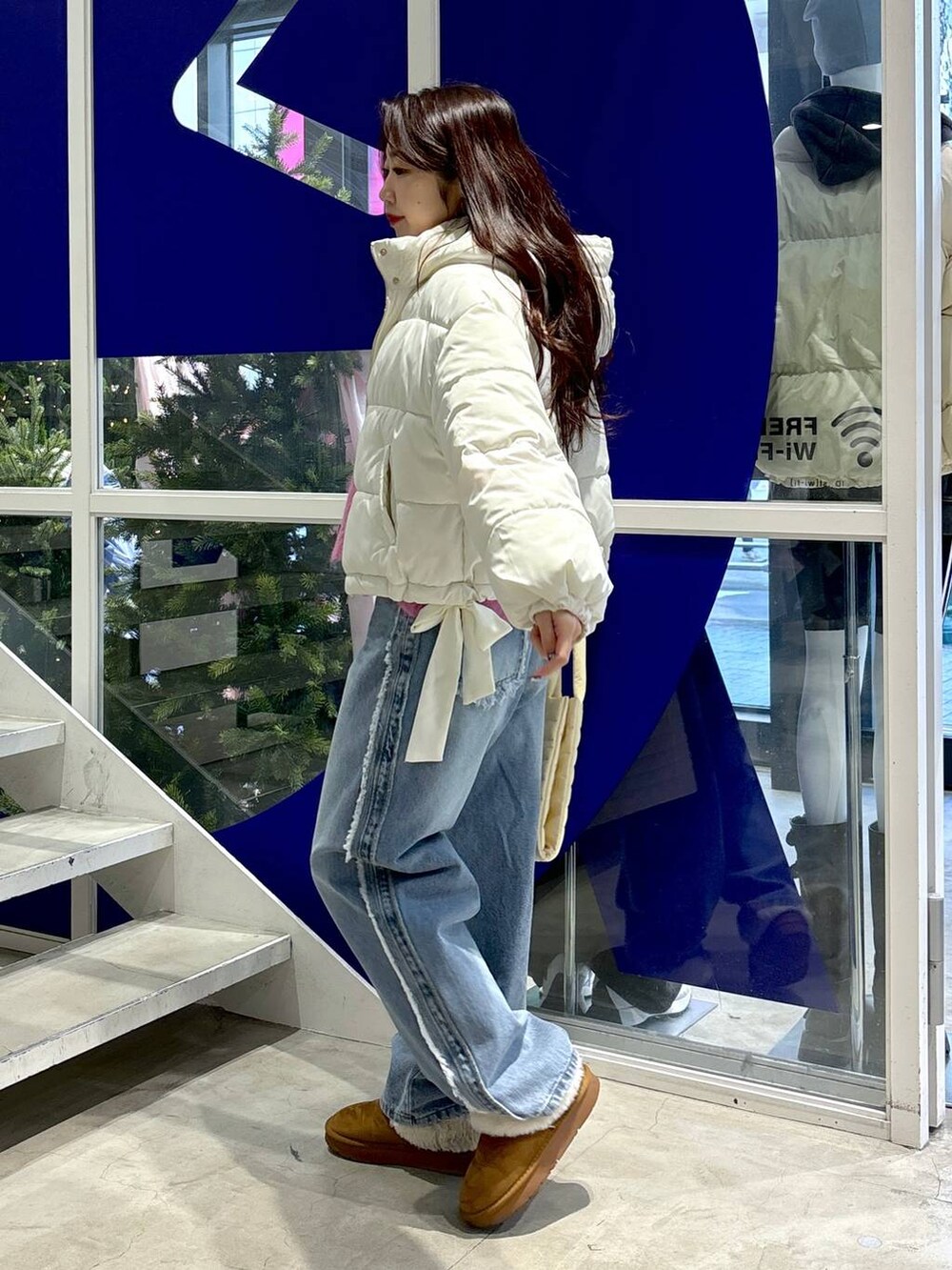 ホワイト系のダウンジャケット/コート、ピンク系のニット/セーター、ブルー系のデニムパンツを着用したレディースの秋コーディネートの4枚目の写真