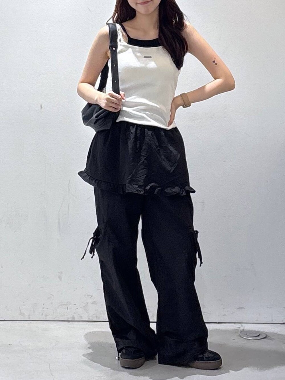 ブラック系のトートバッグ、ホワイト系のタンクトップ、ブラック系のカーゴパンツを着用したレディースの夏コーディネートの2枚目の写真