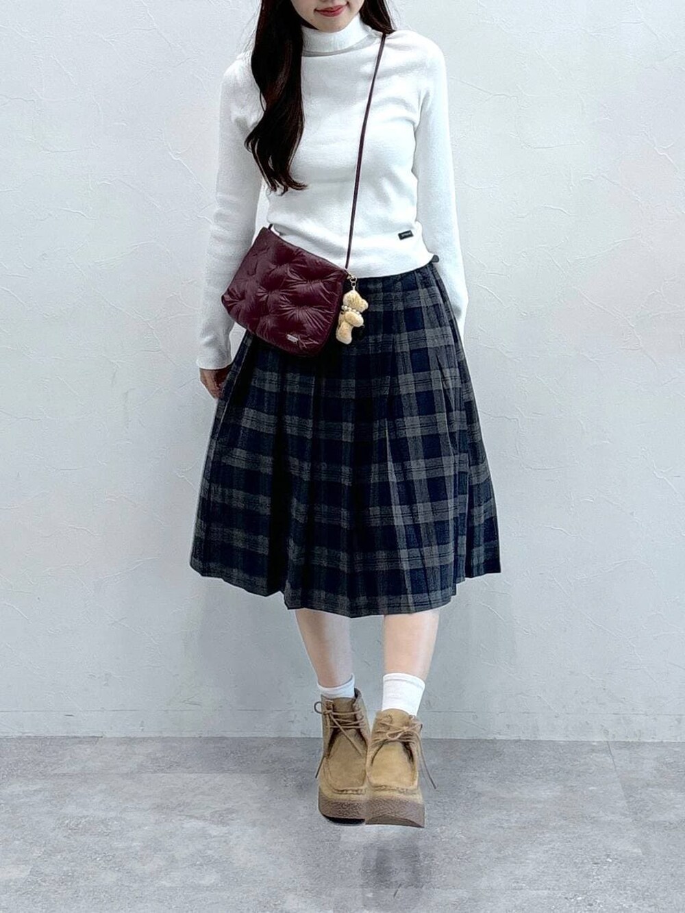 グレー系のスカート、ホワイト系のニット/セーター、ベージュ系のキーホルダーを着用したレディースの秋コーディネートの2枚目の写真