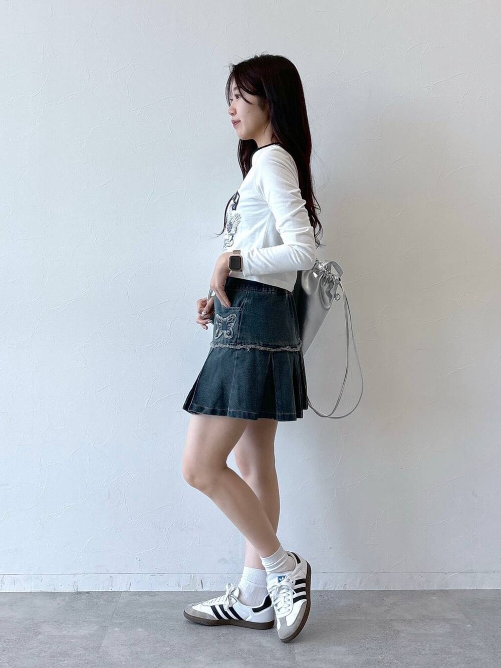 ブルー系のデニムスカート、ホワイト系のTシャツ/カットソー、グレー系のバックパック/リュックを着用したレディースの秋コーディネートの3枚目の写真