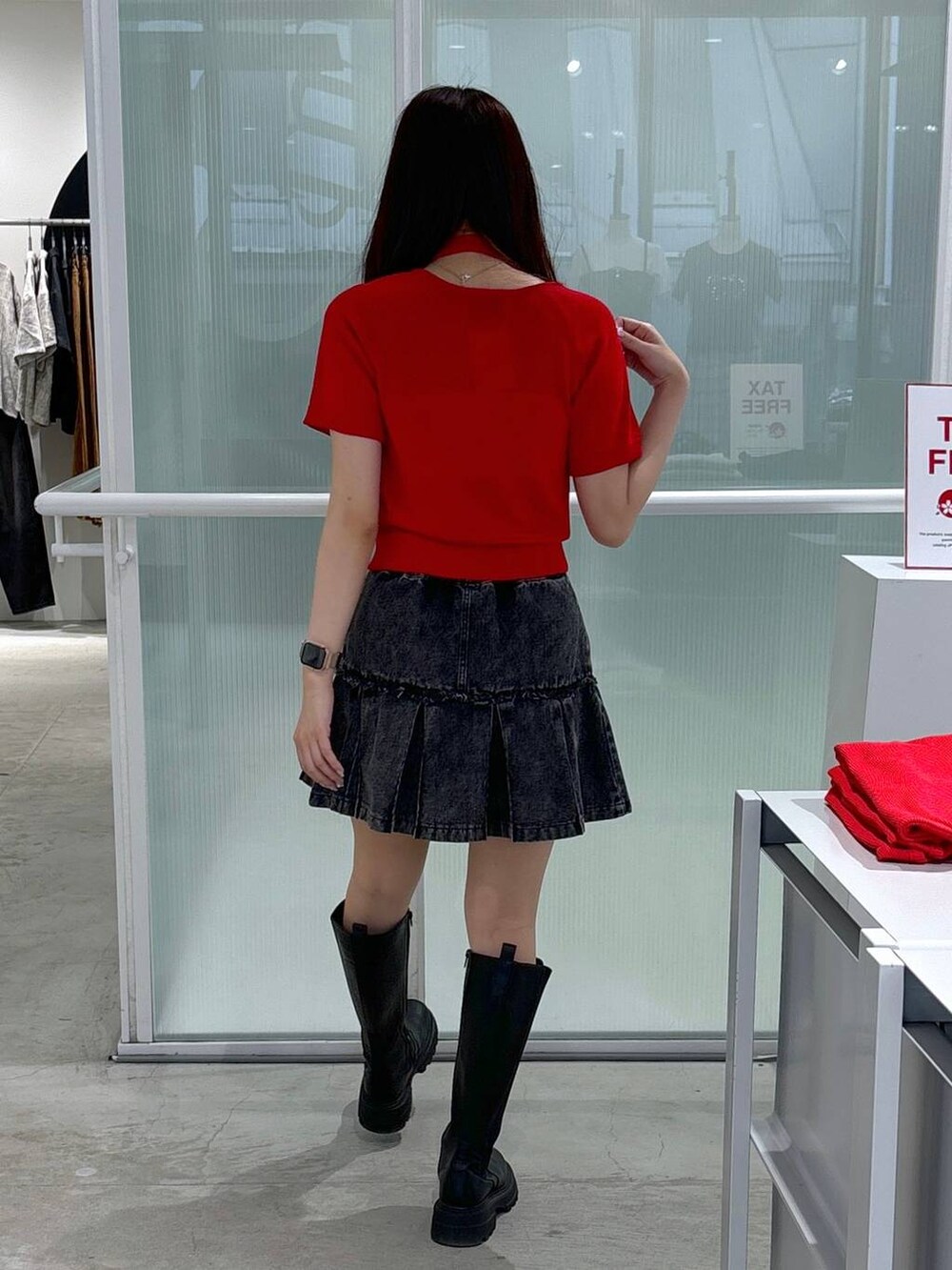 レッド系のニット/セーター、ブラック系のブーツ、ブラック系のデニムスカートを着用したレディースの夏コーディネートの4枚目の写真