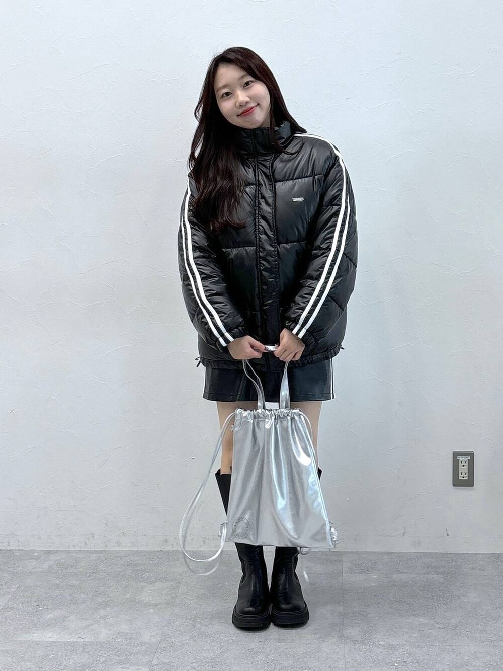 ブラック系のスカート、ブラック系のダウンジャケット/コート、ブラック系のブーツを着用したレディースの秋コーディネートの3枚目の写真