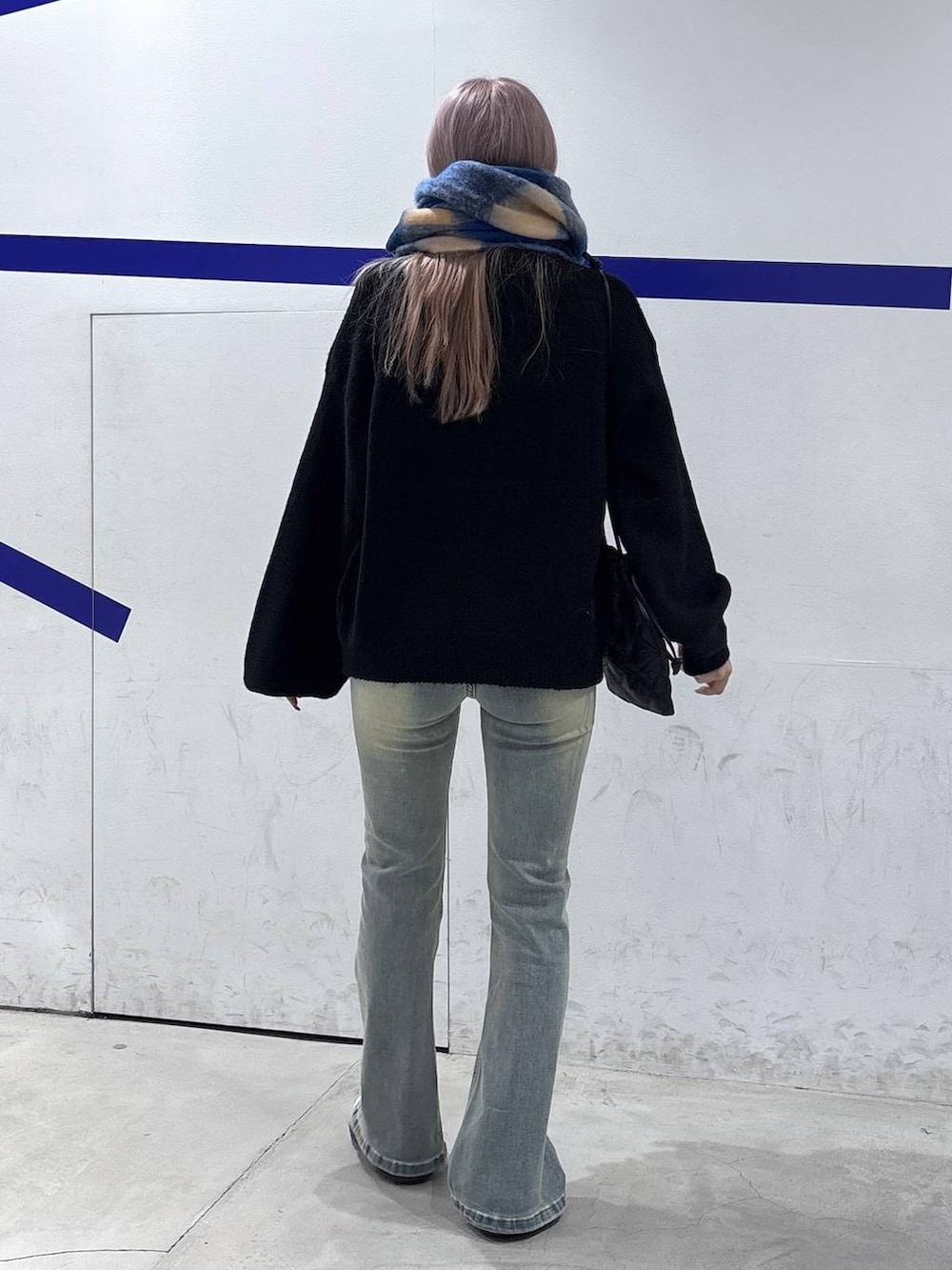 ブルー系のデニムパンツ、ブラック系のニット/セーター、ブラック系のショルダーバッグを着用したレディースの秋コーディネートの5枚目の写真