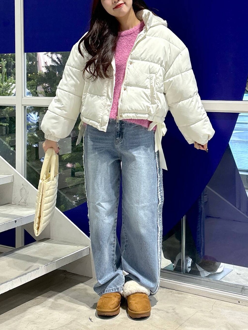 ホワイト系のダウンジャケット/コート、ピンク系のニット/セーター、ブルー系のデニムパンツを着用したレディースの秋コーディネートの2枚目の写真