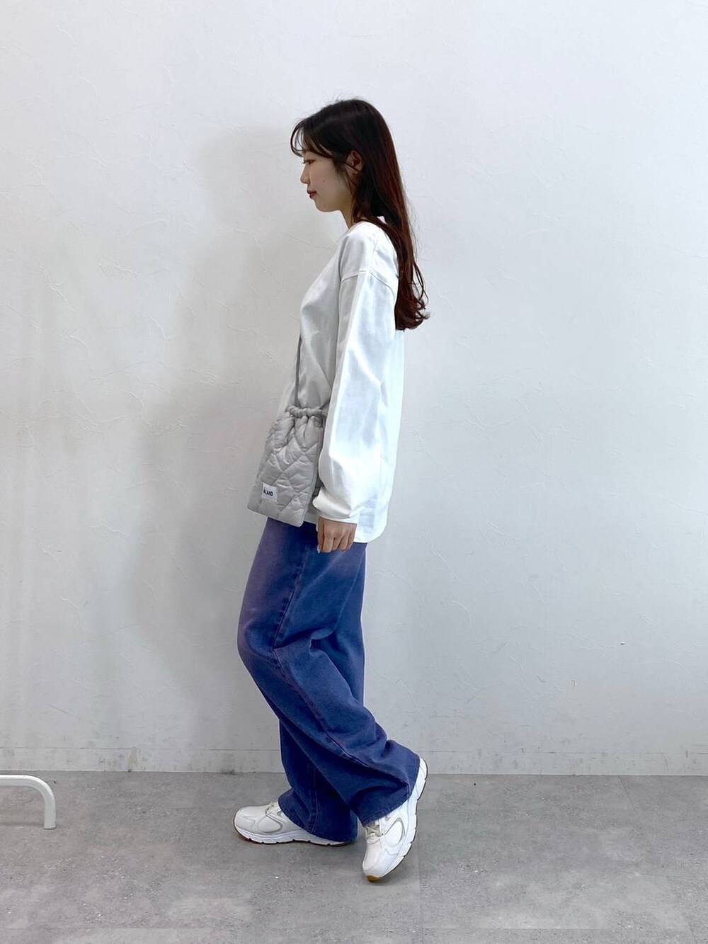 パープル系のデニムパンツ、グレー系のショルダーバッグ、ホワイト系のTシャツ/カットソーを着用したレディースの冬コーディネートの3枚目の写真