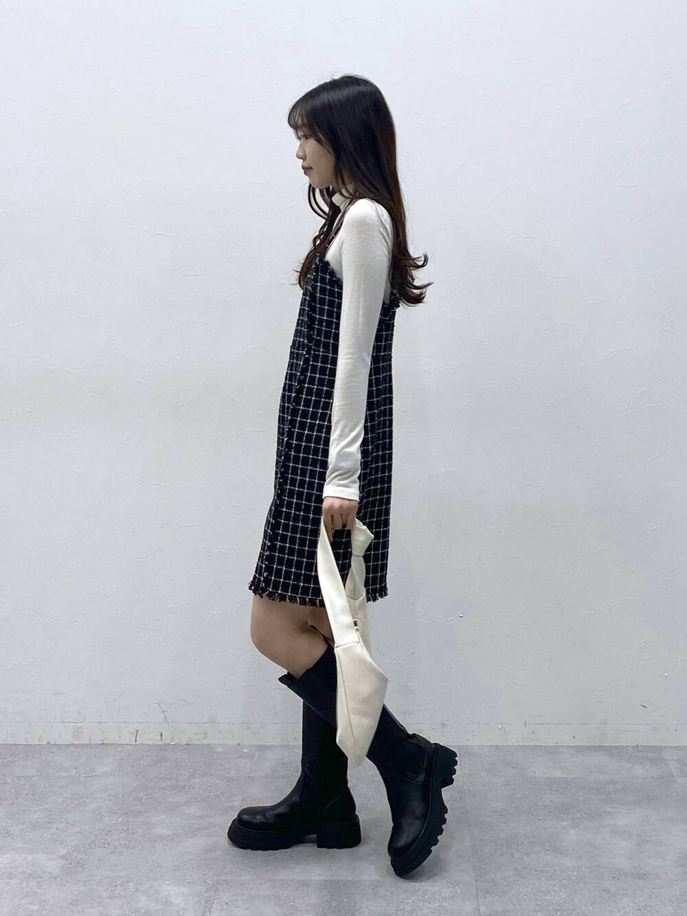 ブラック系のブーツ、ベージュ系のTシャツ/カットソー、ブラック系のワンピースを着用したレディースの冬コーディネートの3枚目の写真