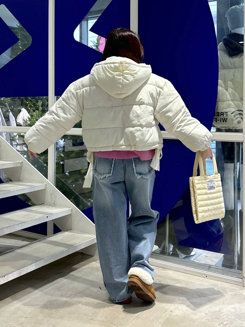 ホワイト系のダウンジャケット/コート、ピンク系のニット/セーター、ブルー系のデニムパンツを着用したレディースの秋コーディネートの6枚目の写真