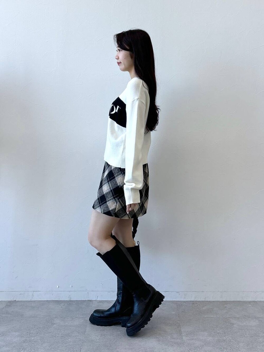 ブラック系のショルダーバッグ、ブラック系のスカート、ブラック系のブーツを着用したレディースの冬コーディネートの3枚目の写真