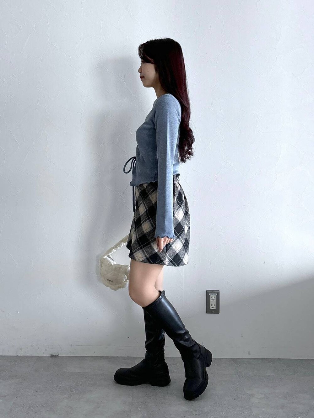 ホワイト系のショルダーバッグ、ブラック系のスカート、ブルー系のTシャツ/カットソーを着用したレディースの冬コーディネートの3枚目の写真