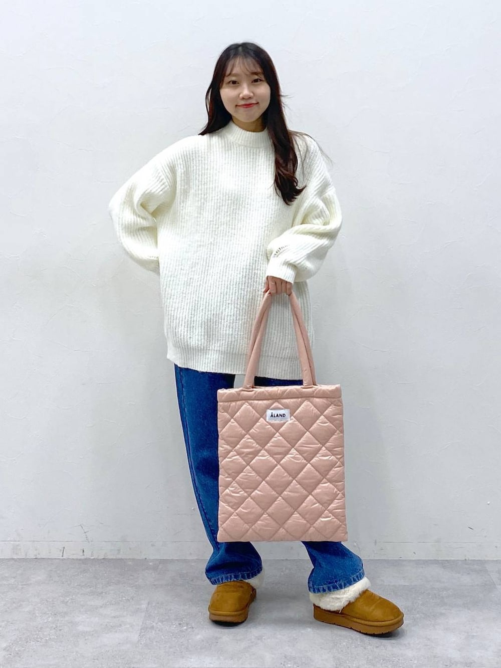 ピンク系のトートバッグ、ブルー系のデニムパンツ、ホワイト系のニット/セーターを着用したレディースの冬コーディネートの2枚目の写真