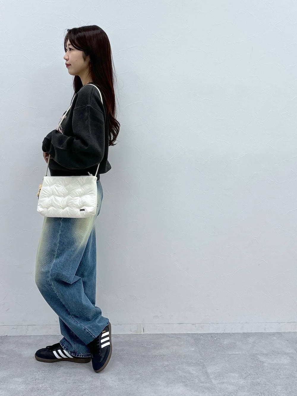 ブルー系のデニムパンツ、ホワイト系のショルダーバッグ、グレー系のニット/セーターを着用したレディースの秋コーディネートの3枚目の写真