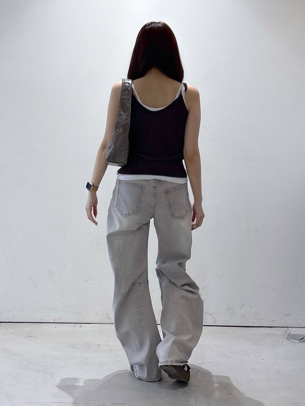 グレー系のデニムパンツ、ブラウン系のタンクトップ、グレー系のハンドバッグを着用したレディースの夏コーディネートの4枚目の写真