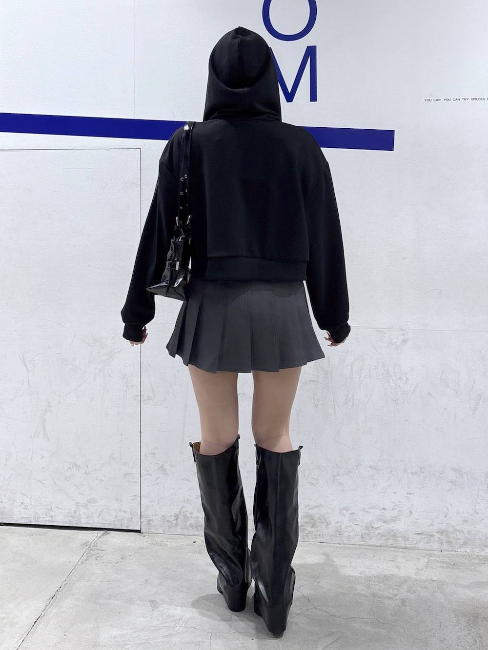 ブラック系のパーカー、ブラック系のブーツ、ブラック系のショルダーバッグを着用したレディースの冬コーディネートの4枚目の写真