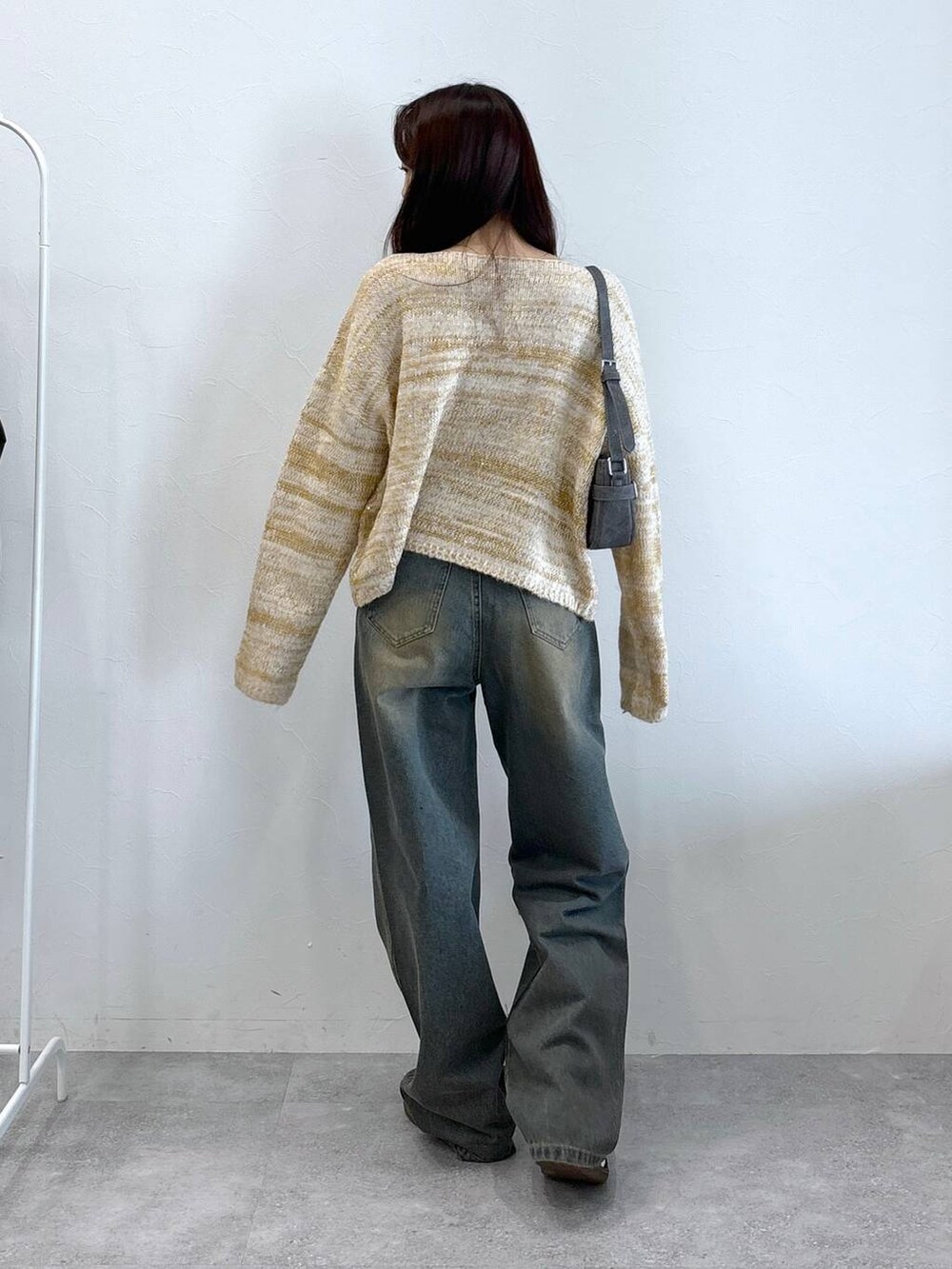 ブラック系のトートバッグ、ブルー系のデニムパンツ、ベージュ系のニット/セーターを着用したレディースの秋コーディネートの4枚目の写真