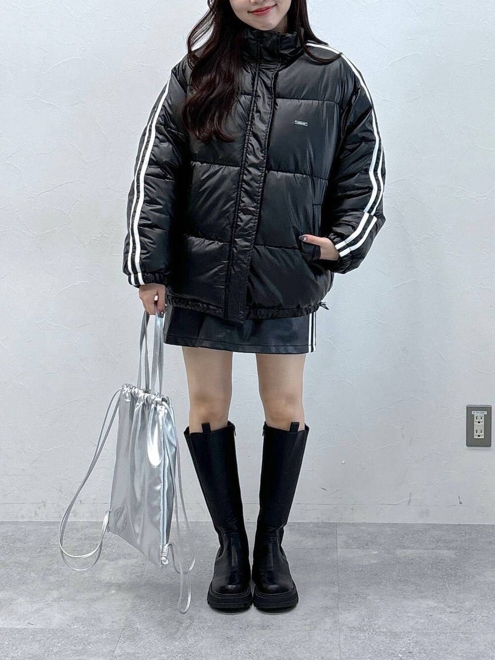 ブラック系のスカート、ブラック系のダウンジャケット/コート、ブラック系のブーツを着用したレディースの秋コーディネートの2枚目の写真