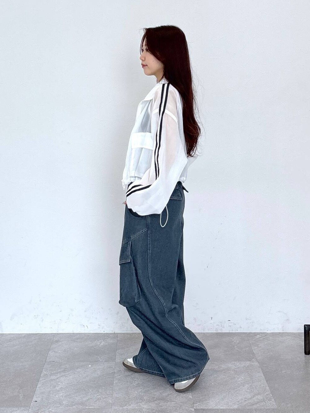 ブルー系のカーゴパンツ、ブラック系のタンクトップ、ホワイト系のブルゾンを着用したレディースの春コーディネートの5枚目の写真