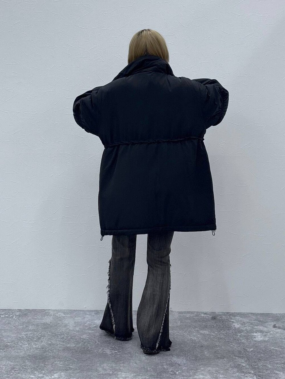 ブラック系のダウンジャケット/コート、レッド系のニット/セーター、ブラック系のデニムパンツを着用したレディースの秋コーディネートの5枚目の写真