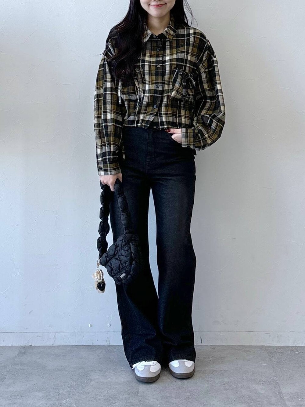 ブラック系のショルダーバッグ、ブラック系のデニムパンツ、イエロー系のシャツ/ブラウスを着用したレディースの冬コーディネートの2枚目の写真