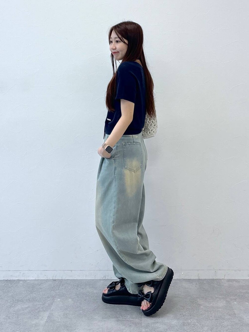 ブルー系のデニムパンツ、ブラック系のサンダル、ベージュ系のトートバッグを着用したレディースの夏コーディネートの4枚目の写真