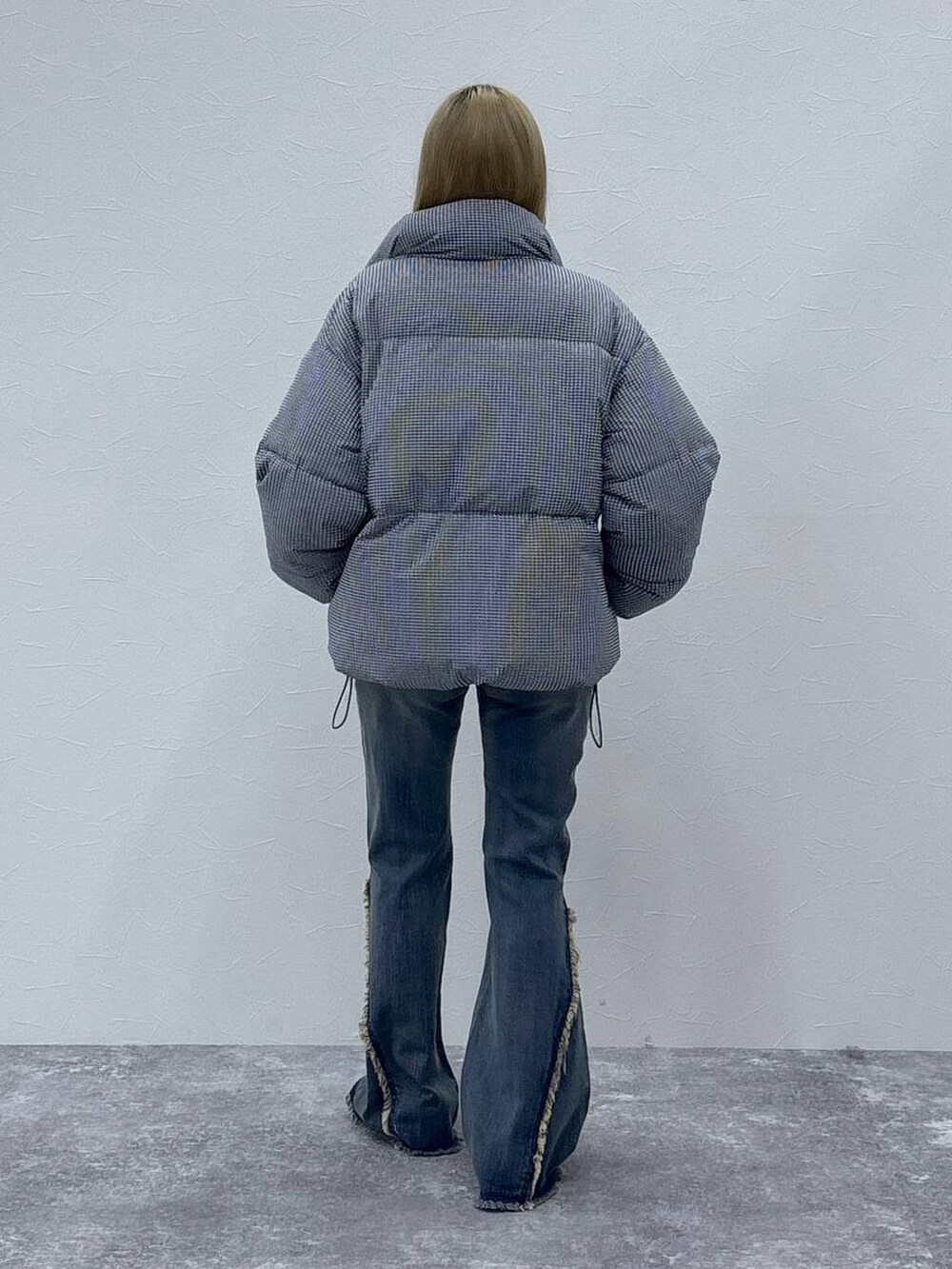ブラック系のダウンジャケット/コート、ホワイト系のニット/セーター、ブラック系のデニムパンツを着用したレディースの秋コーディネートの5枚目の写真