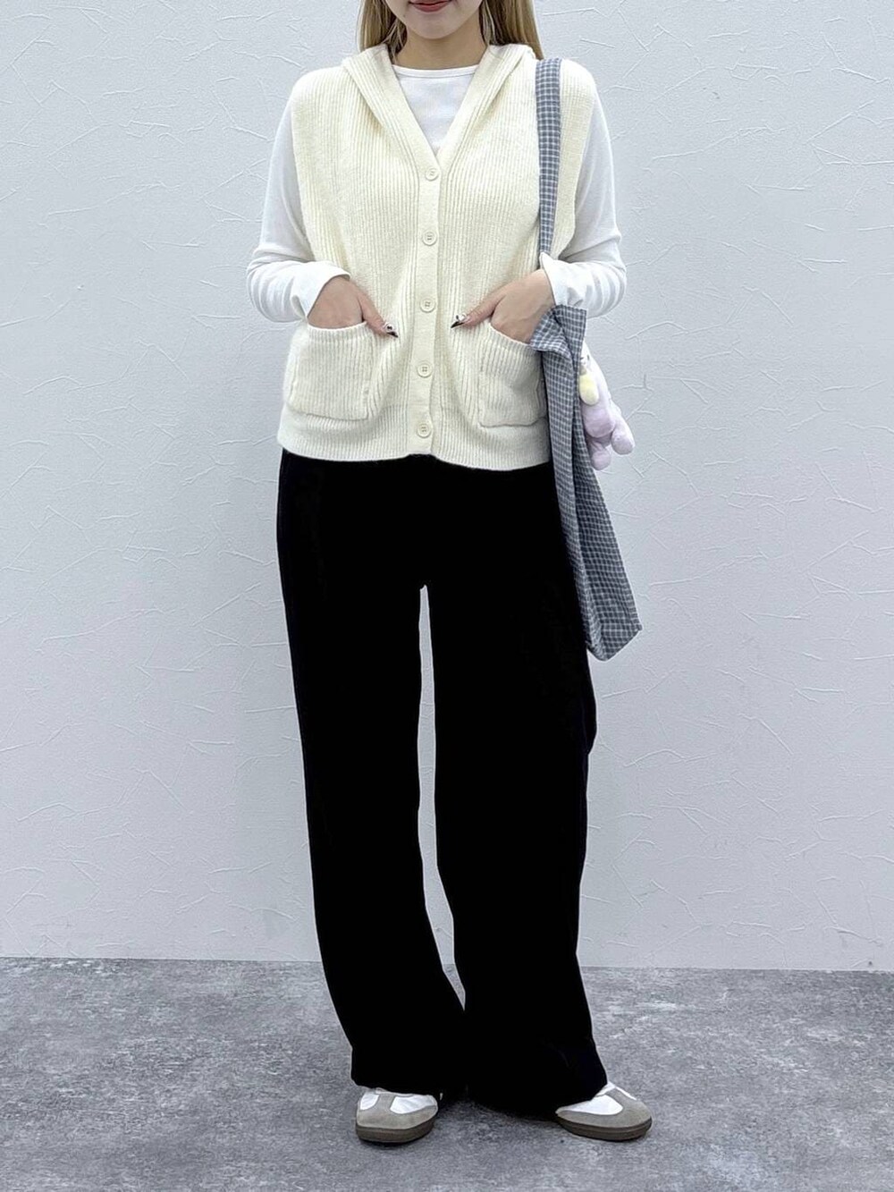 グレー系のトートバッグ、ホワイト系のベストを着用したレディースの冬コーディネートの2枚目の写真