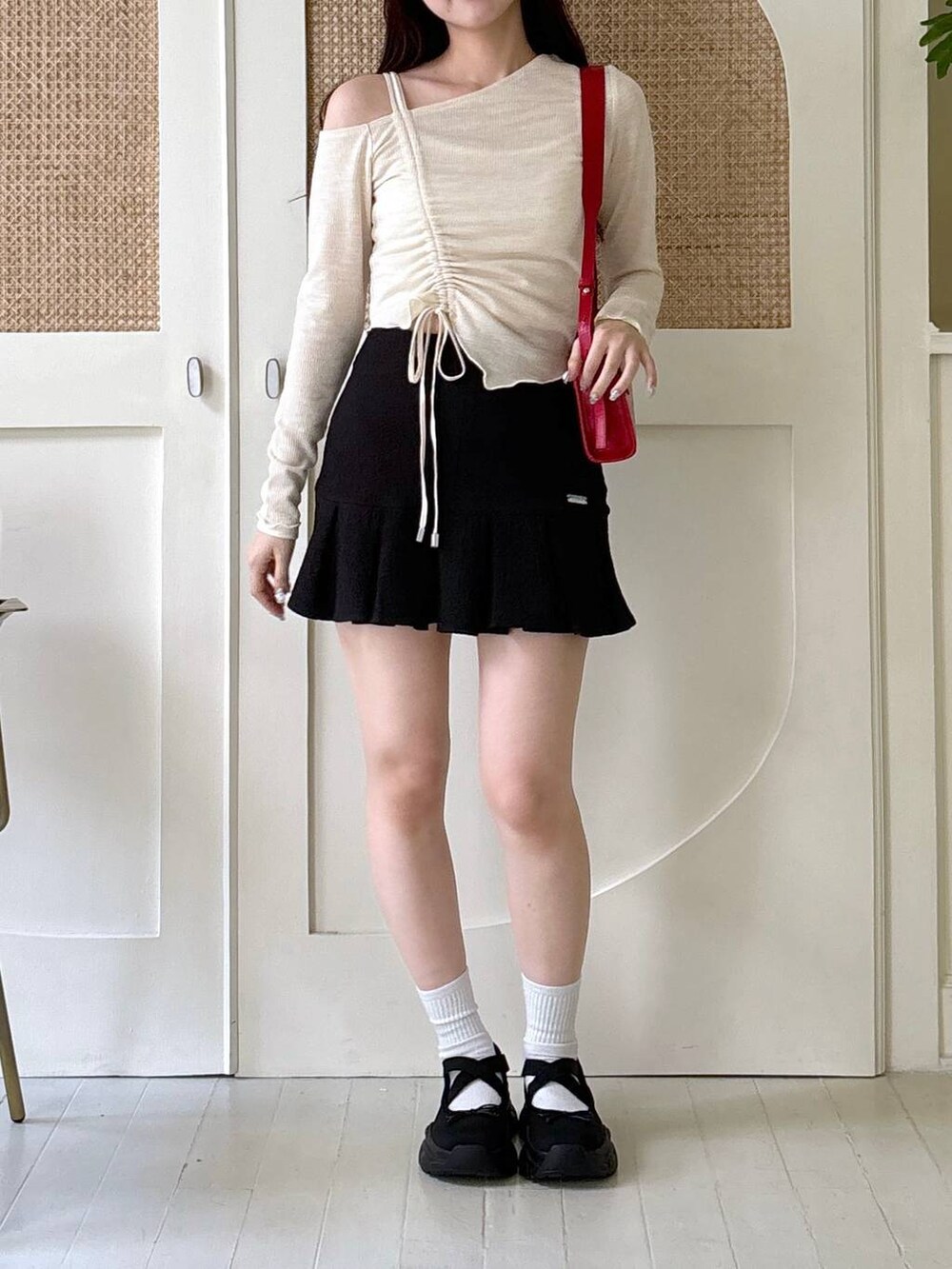 レッド系のショルダーバッグ、ベージュ系のTシャツ/カットソー、ブラック系のスカートを着用したレディースの秋コーディネートの3枚目の写真