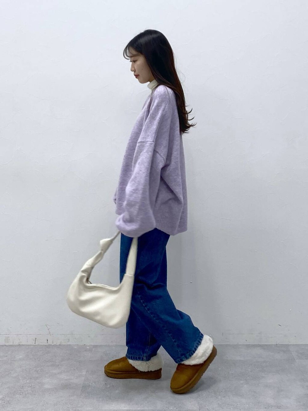 ブルー系のデニムパンツ、ベージュ系のTシャツ/カットソー、パープル系のニット/セーターを着用したレディースの冬コーディネートの3枚目の写真