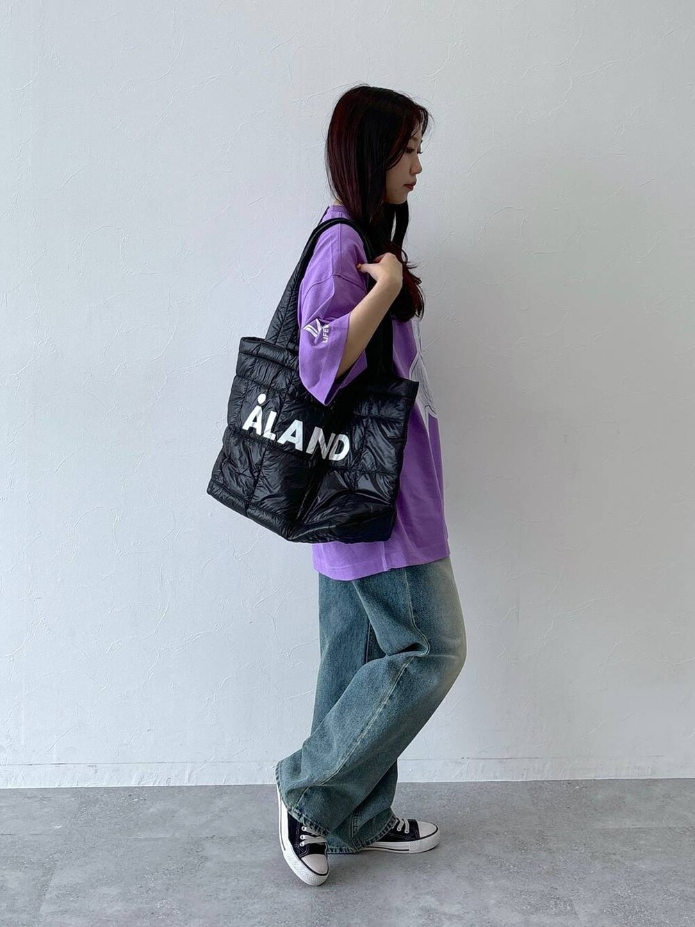 ブルー系のデニムパンツ、ブラック系のボストンバッグ、パープル系のTシャツ/カットソーを着用したレディースの夏コーディネートの4枚目の写真