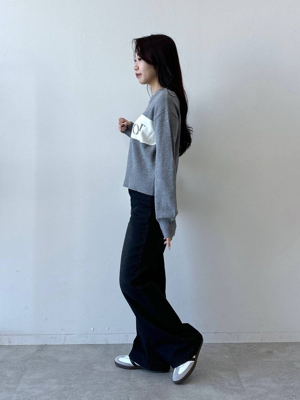 ホワイト系のショルダーバッグ、ブラック系のデニムパンツ、グレー系のニット/セーターを着用したレディースの冬コーディネートの3枚目の写真