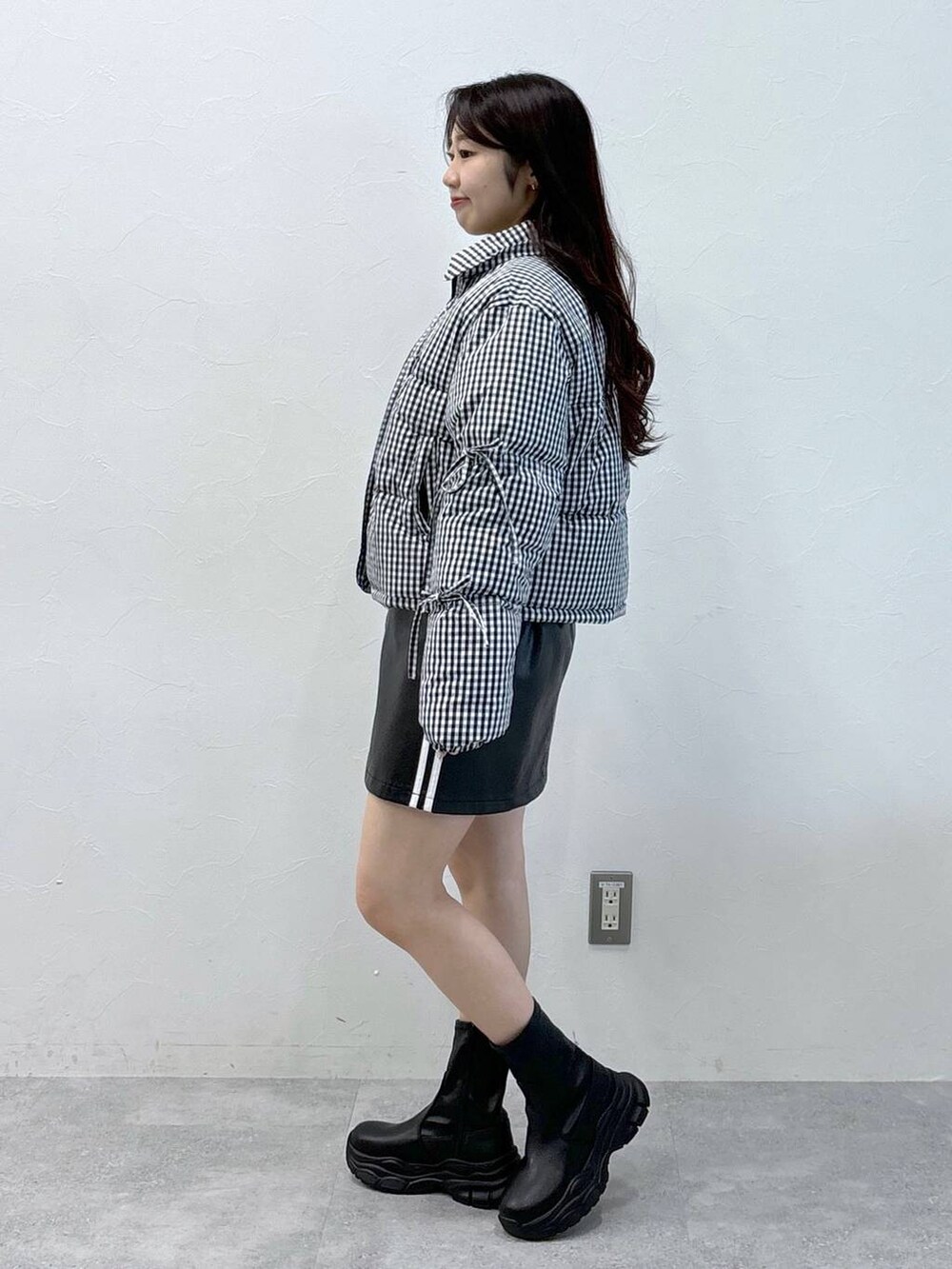 グレー系のニット/セーター、ブラック系のスカート、ブラック系のダウンジャケット/コートを着用したレディースの秋コーディネートの3枚目の写真