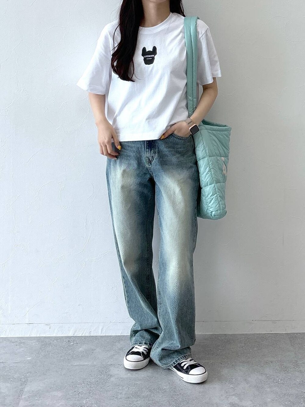 ブルー系のデニムパンツ、グリーン系のショルダーバッグ、ホワイト系のTシャツ/カットソーを着用したレディースの夏コーディネートの2枚目の写真