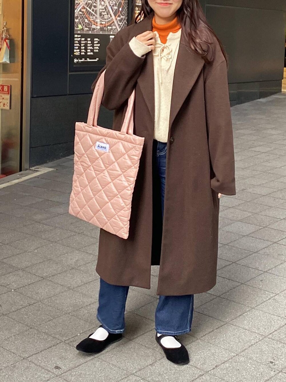 ブラック系のパンプス、ピンク系のトートバッグ、オレンジ系のニット/セーターを着用したレディースの冬コーディネートの2枚目の写真