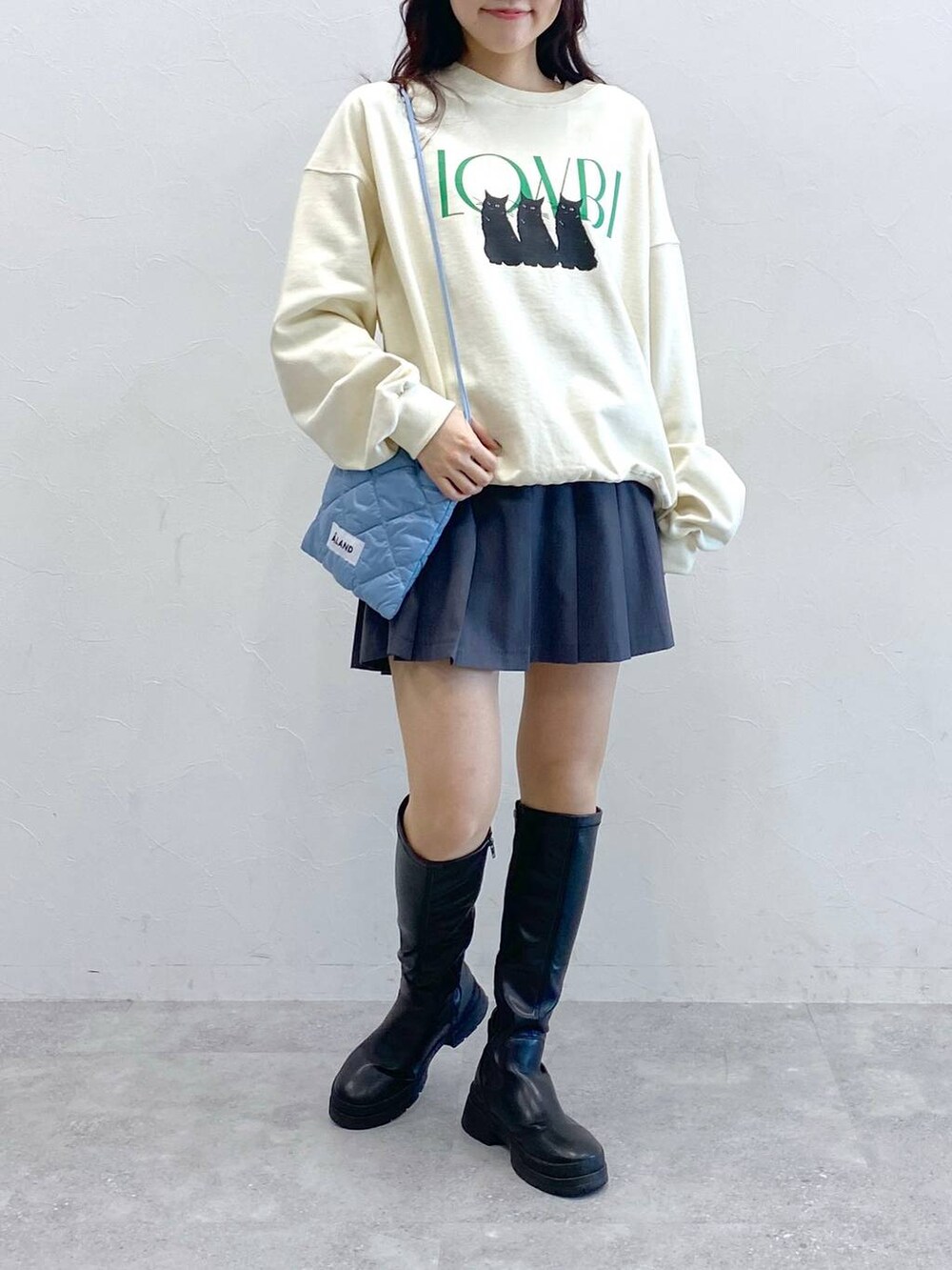 ホワイト系のスウェット、ブルー系のショルダーバッグ、グレー系のスカートを着用したレディースの冬コーディネートの3枚目の写真