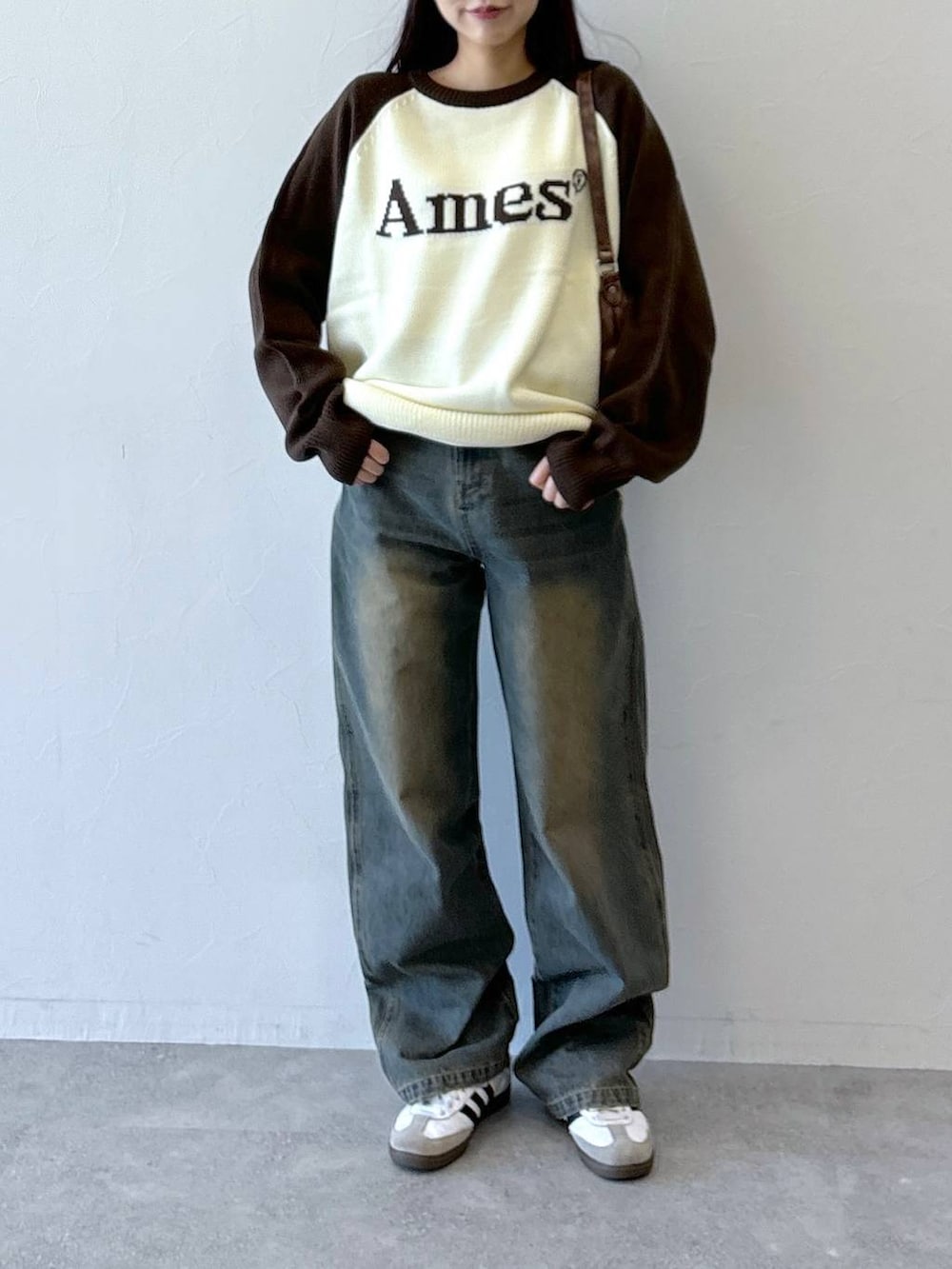 ブラウン系のニット/セーター、ブルー系のデニムパンツ、ブラウン系のハンドバッグを着用したレディースの冬コーディネートの2枚目の写真