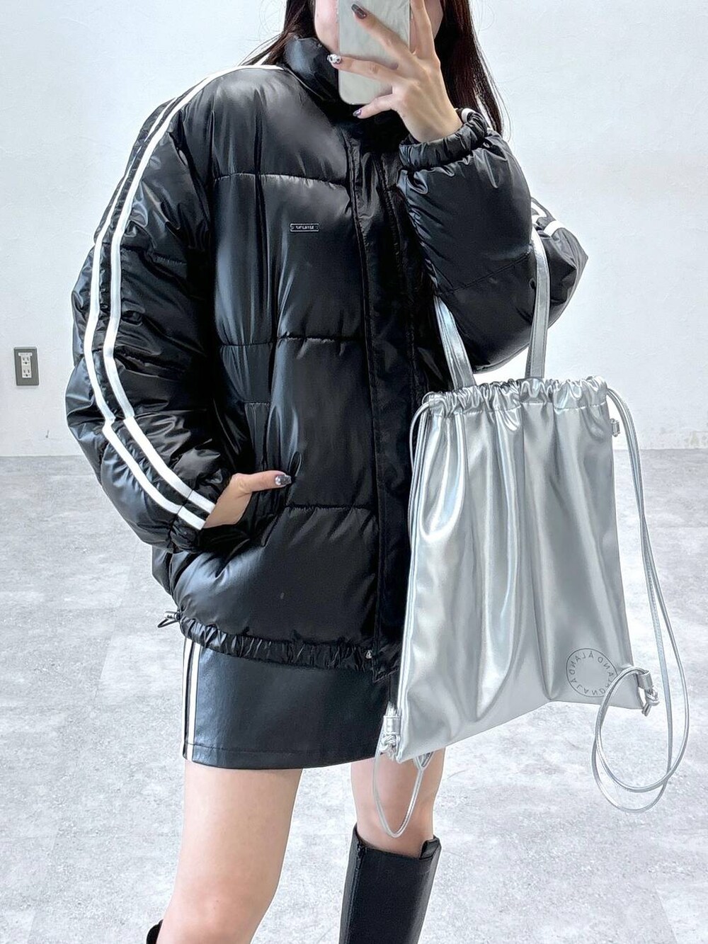 ブラック系のスカート、ブラック系のダウンジャケット/コート、ブラック系のブーツを着用したレディースの秋コーディネートの6枚目の写真